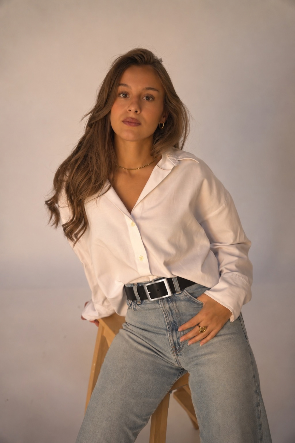 Ceinture Charlotte Atelier Nappa en cuir noir à boucle rectangulaire argentée, portée sur un jean taille haute avec une chemise blanche