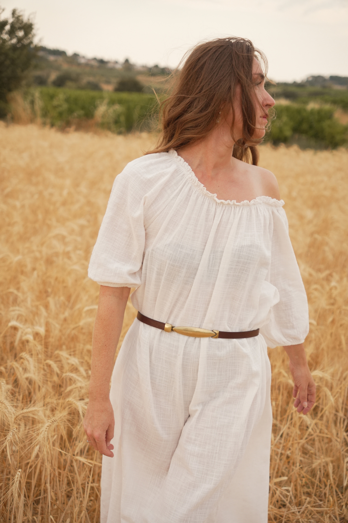 Ceinture femme très fine Rachel Atelier Nappa, cuir marron et boucle dorée, sur une robe bohème en lin blanc