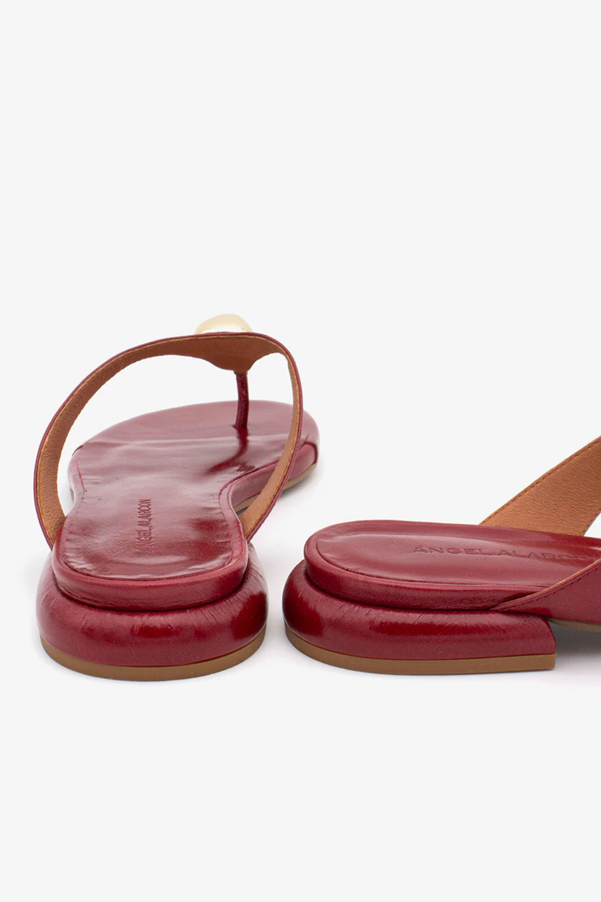 Détail médaillon doré et semelle bombée sandales Claudia cuir rouge bordeaux