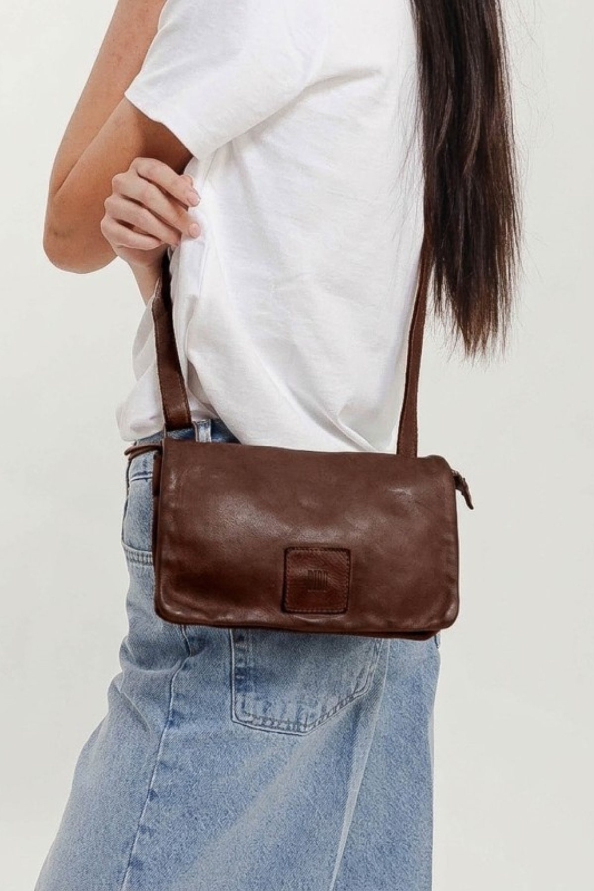 Petit sac à rabat en cuir camel Biba Boston BT33 porté à l’épaule avec un jean