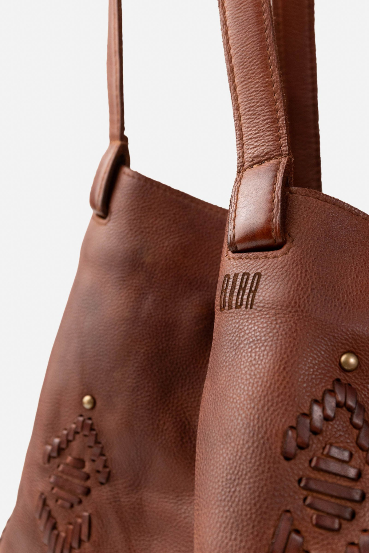 Détail du sac cabas Bayron Biba en cuir camel : signature gravée, anse cousue main et tissage ethnique