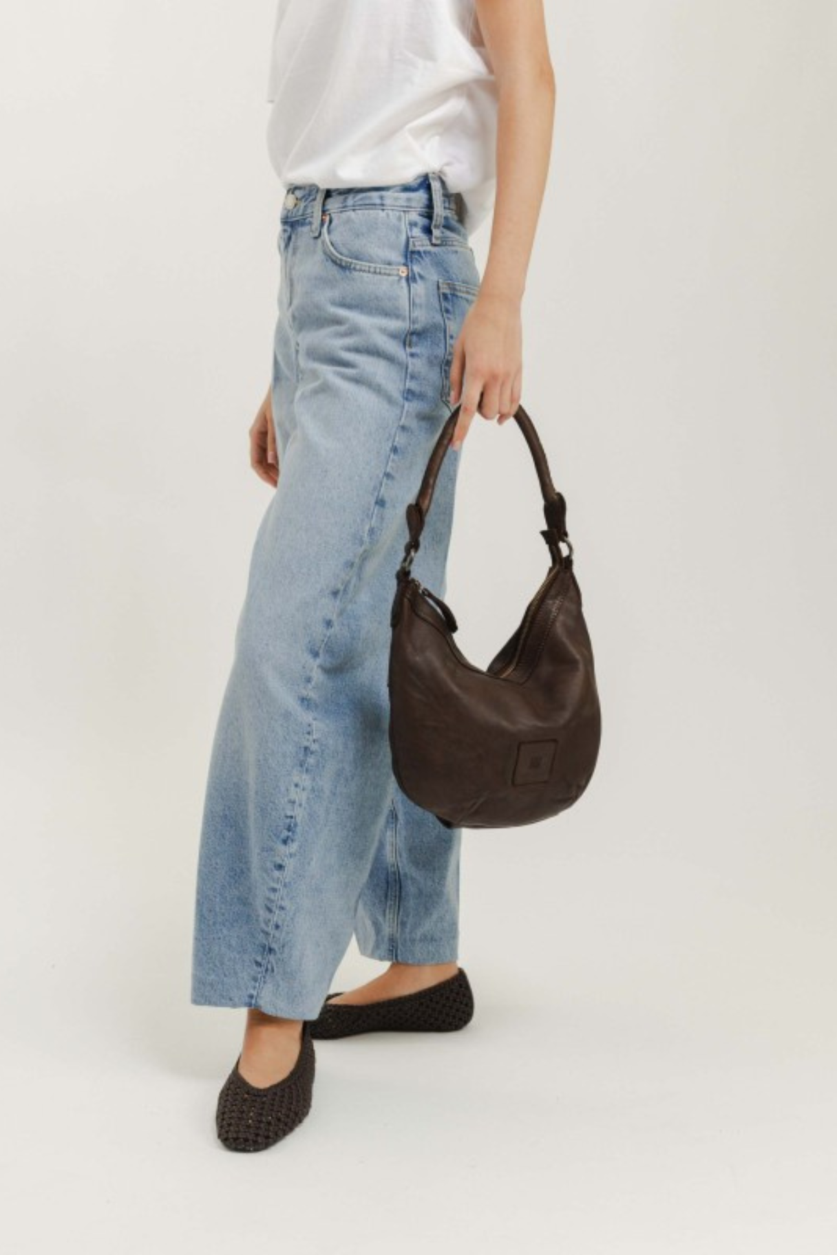 Sac besace demi-lune en cuir marron foncé porté à la main, maroquinerie Nappa