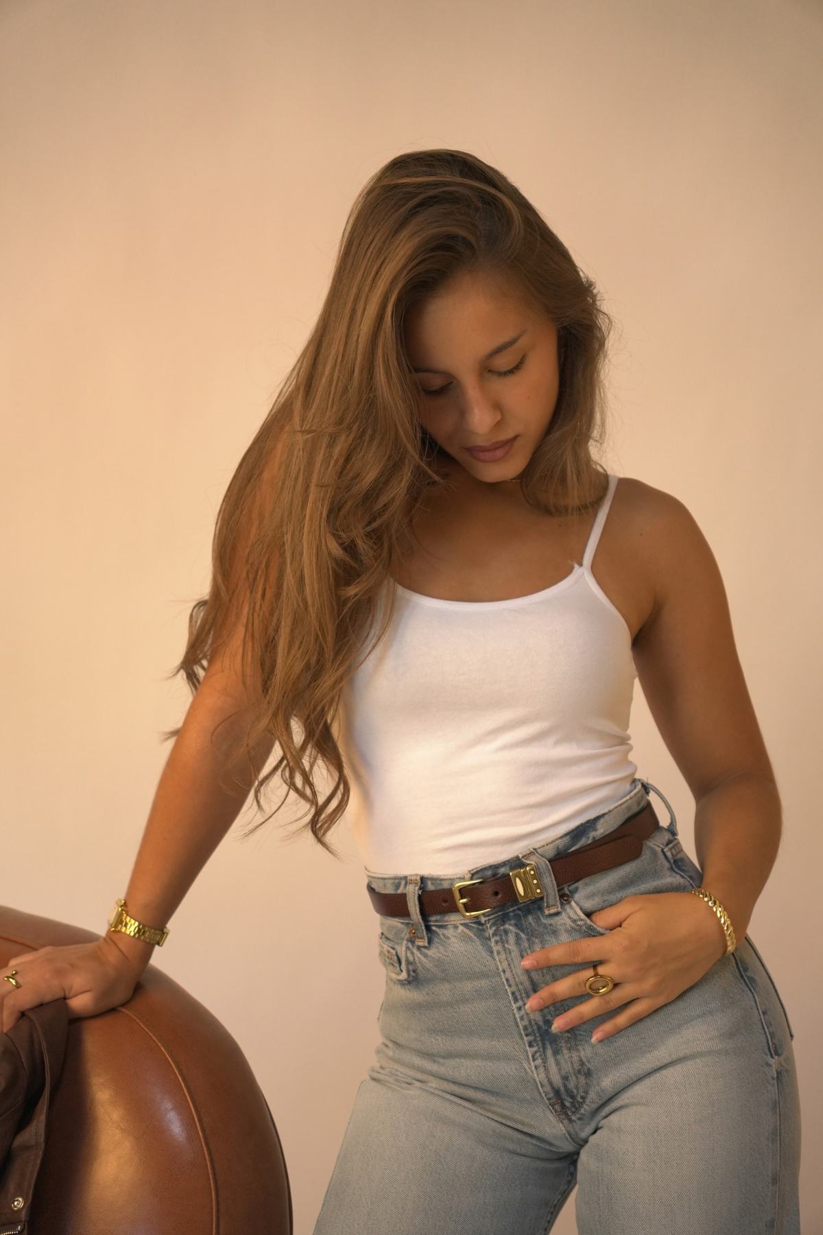 Ceinture fine Arwen Atelier Nappa en cuir chocolat, boucle et passants dorés, portée sur un jean taille haute avec un débardeur blanc