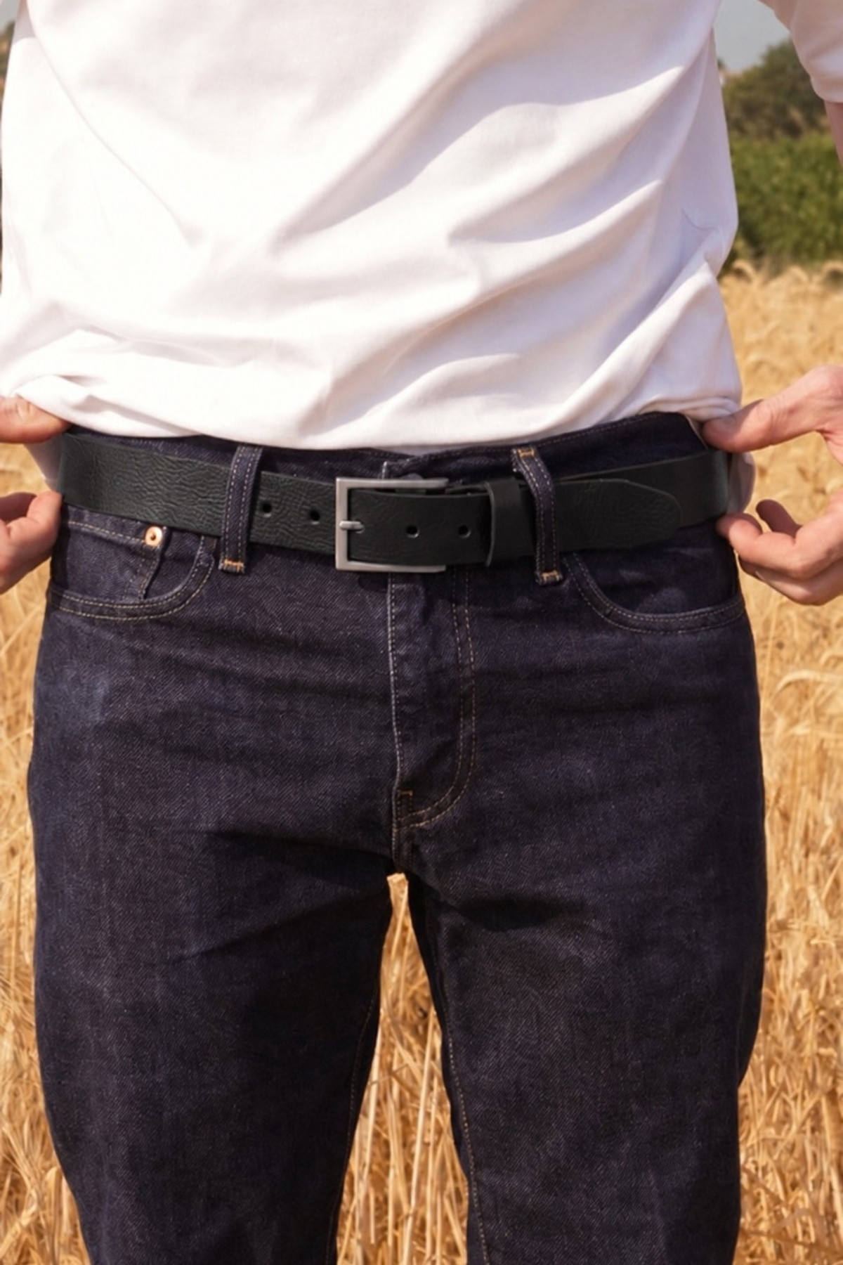 Ceinture en cuir noir pour homme Roger Atelier Nappa, boucle rectangulaire argentée, sur un jean brut dans un champ de blé