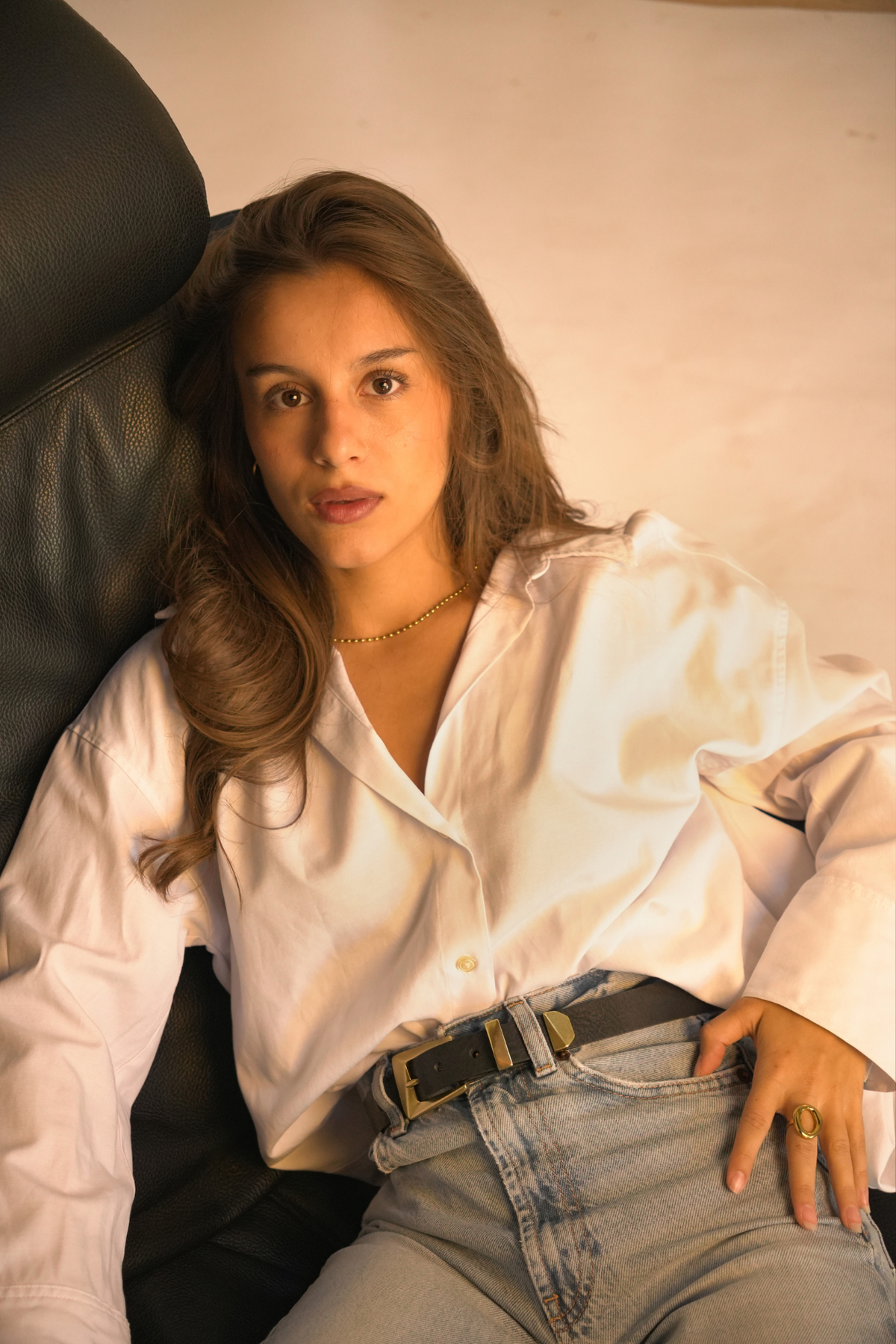Ceinture western Monique Atelier Nappa en cuir noir à boucle dorée facettée, portée avec une chemise blanche et un jean clair