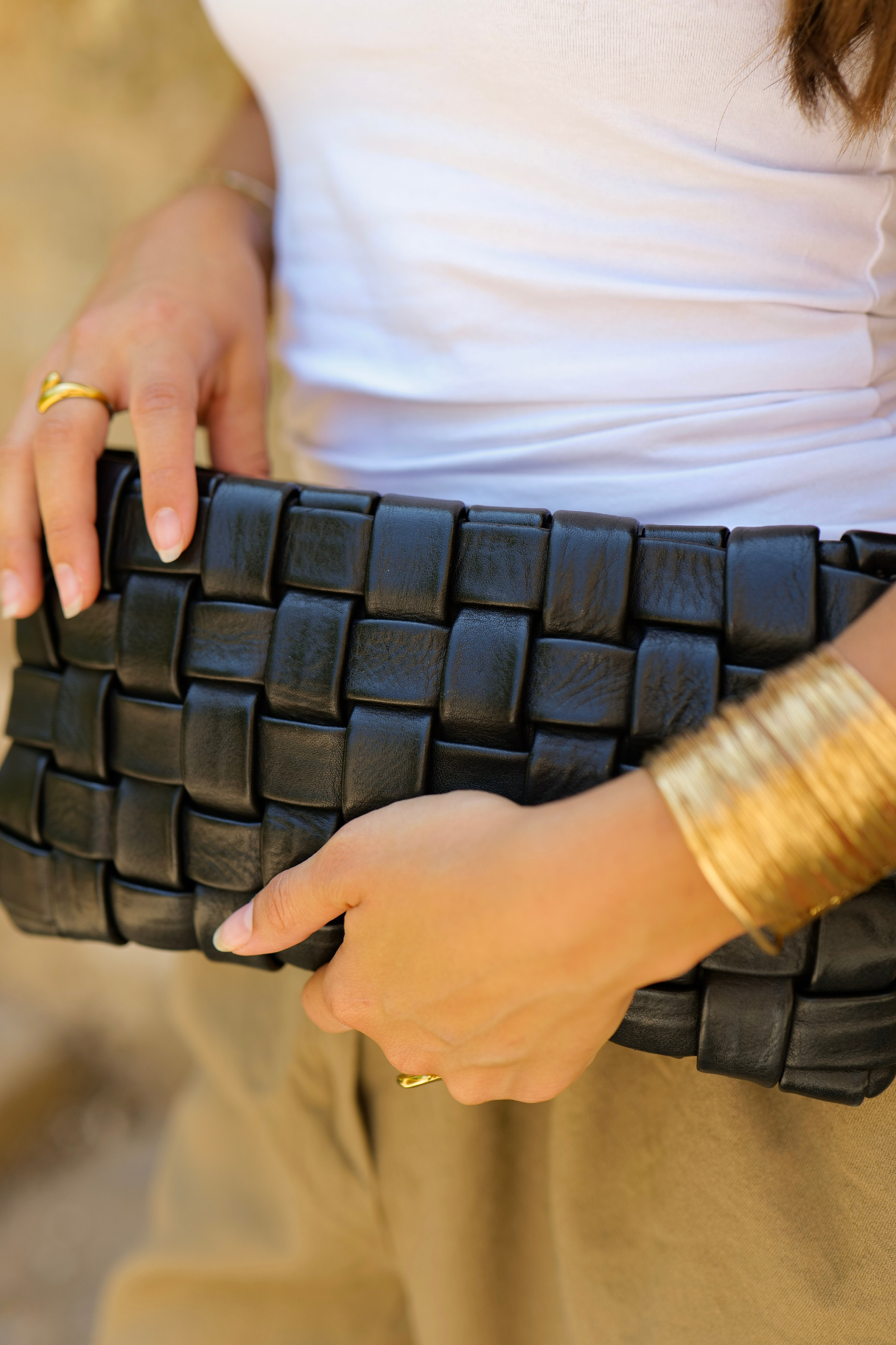 Gros plan sur le tressage d’un sac en cuir noir tenu à la main