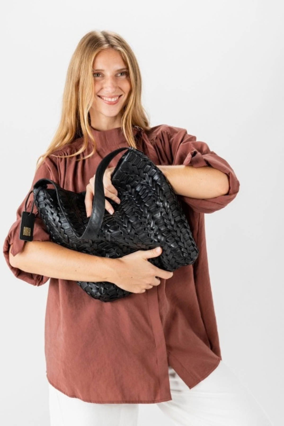 Sac hobo Biba en cuir tressé chevron noir tenu dans les bras, détail du relief