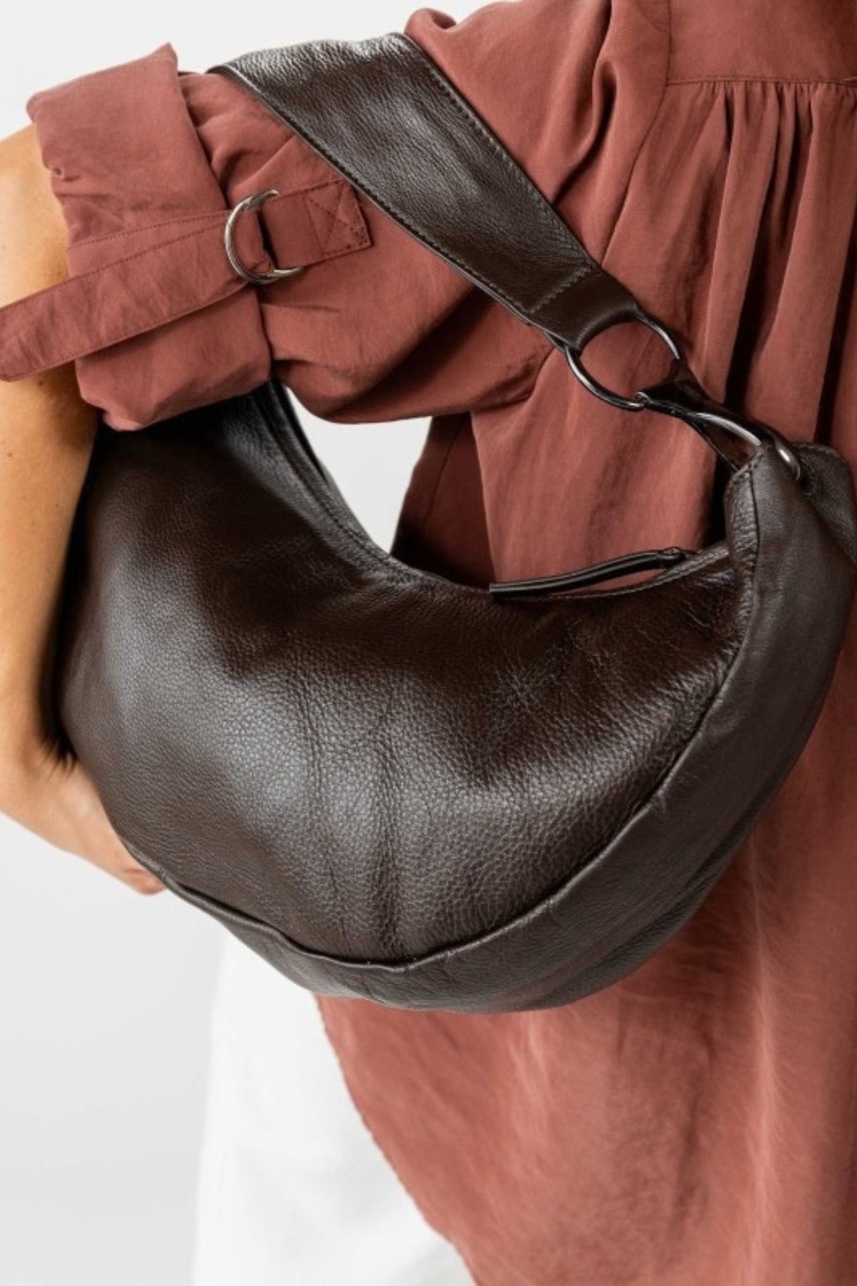 Sac Jackpot Biba en cuir lavé marron porté à l'épaule, détail de l'anse et du mousqueton