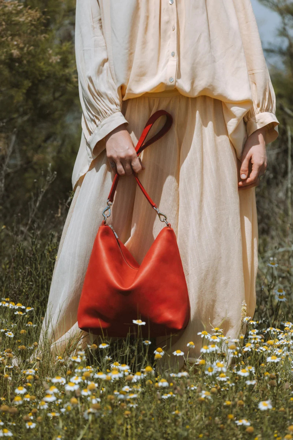 Sac seau zippé en cuir orange Iliade Ateliers Fourès tenu à la main, cuir pleine fleur fabriqué en France